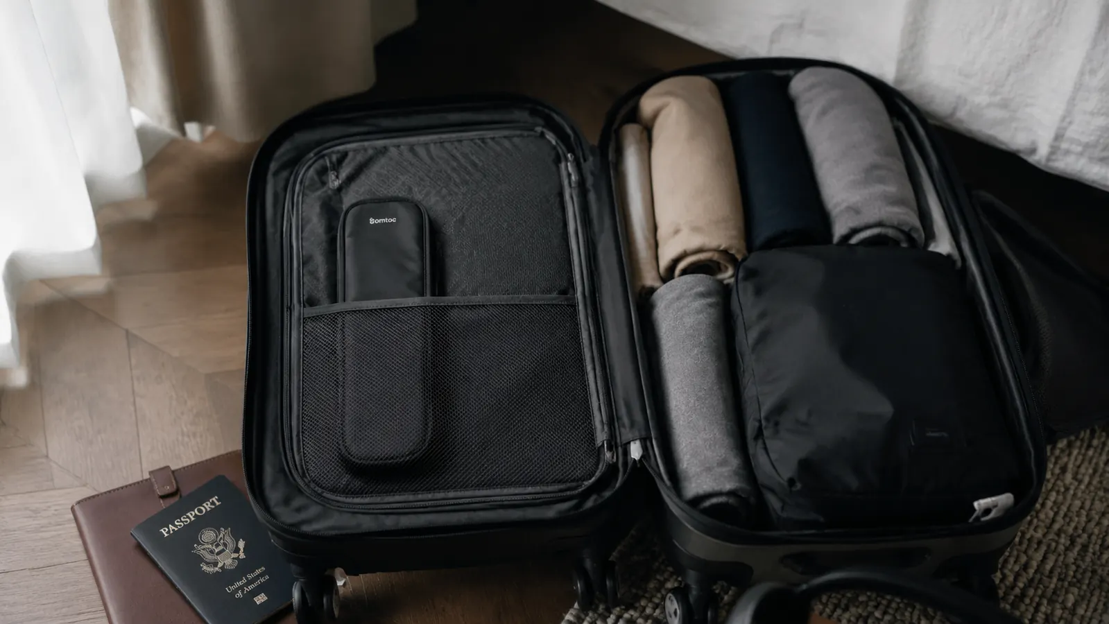FYY cable organizer closed and sitting upright in the outer pocket of an open carry-on suitcase ready for travel