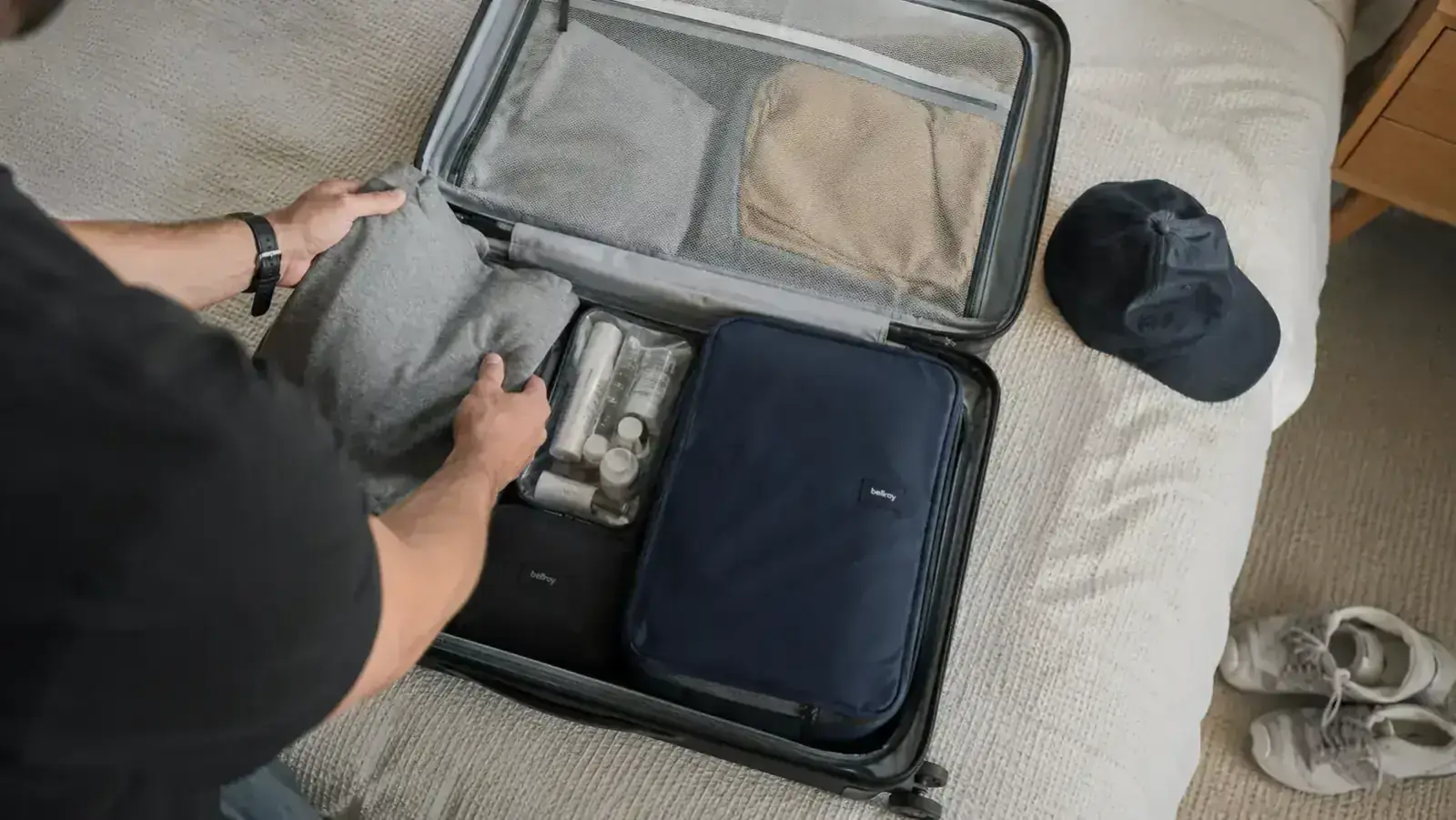 FYY cable organizer sitting inside an open carry-on suitcase next to a toiletry bag and packing cube
